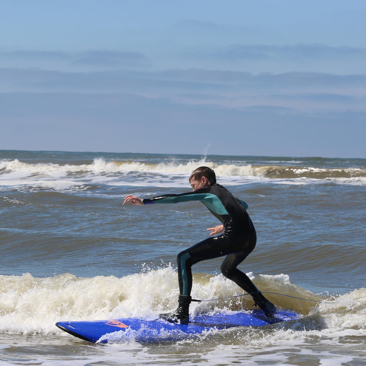 Jongen op een surfplank in de golven.